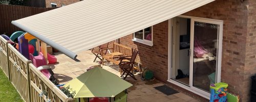 Beige awning above a patio filled with children's toys.